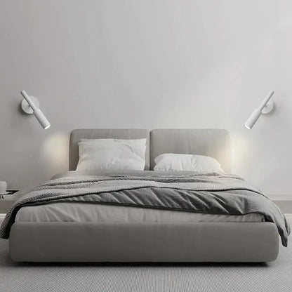 Modern matte black adjustable led wall lamp installed above a gray upholstered bed with matching headboard and footboard