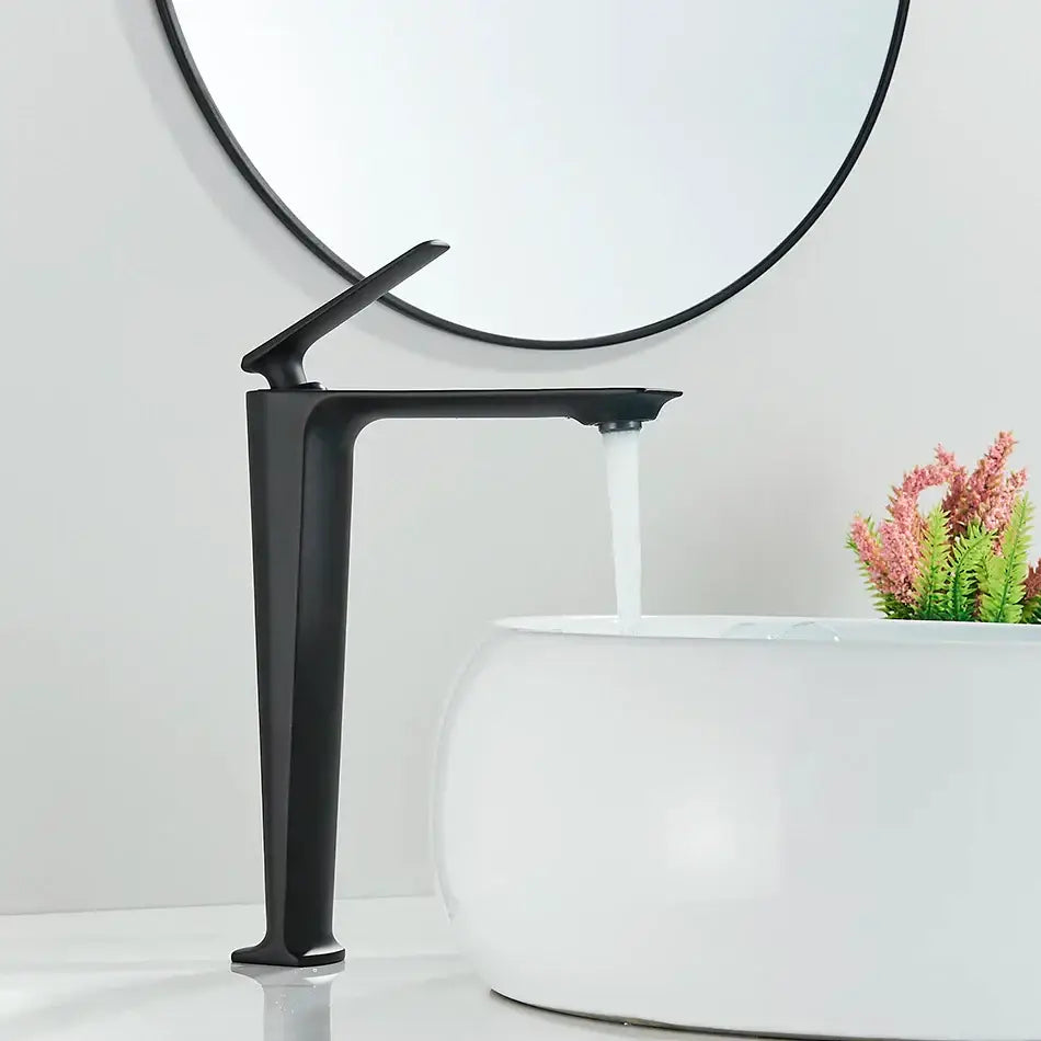 Modern matte black basin mixer with sleek angular design and tall spout flowing water into white ceramic sink decorbites black basin