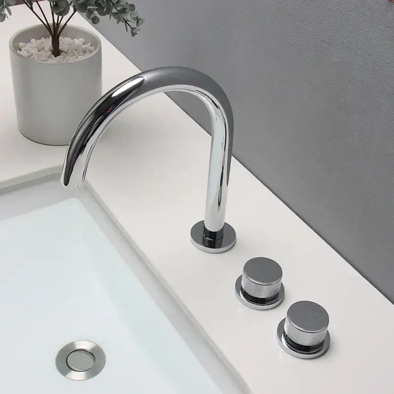 Modern chrome-finished basin faucet with sleek curved spout and brushed gold basin faucet handles for bathroom sinks