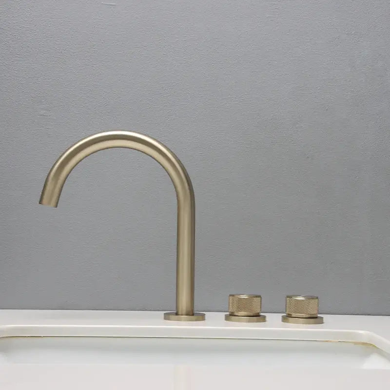 Modern brushed brass basin faucet with curved spout and two textured knobs in brushed gold basin bathroom sink design