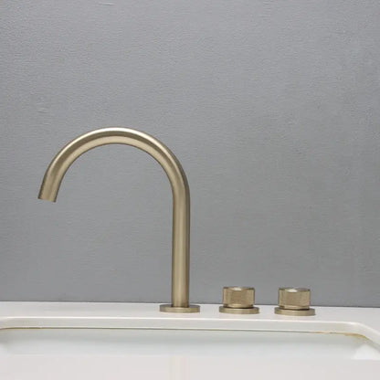 Modern brushed brass basin faucet with curved spout and two textured knobs in brushed gold basin bathroom sink design