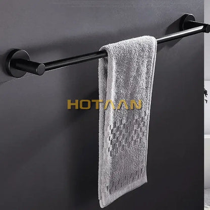 A soft gray towel hangs on a modern matte black wall mounted towel bar with wood accents in a bathroom