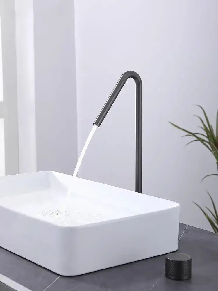 Modern matte brushed black basin faucet with a sleek curved spout pouring water into a white vessel sink decorbites brushed black