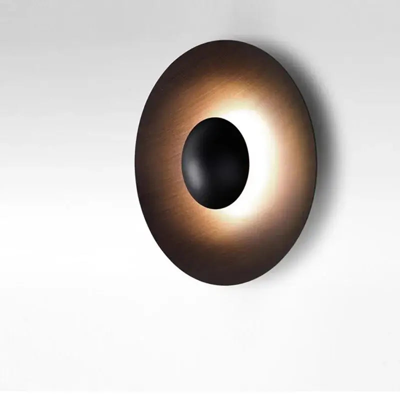 Bronze-finished circular ginger round wall lamp with central black oval cutout emitting warm light for bedroom decorbites ginger round
