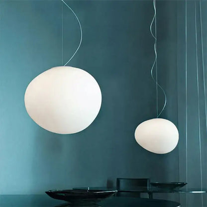 Two white matte glass gregg glass pendant lights with thin metallic cords hang against a dark teal wall for kitchen decorbites gregg glass pendant
