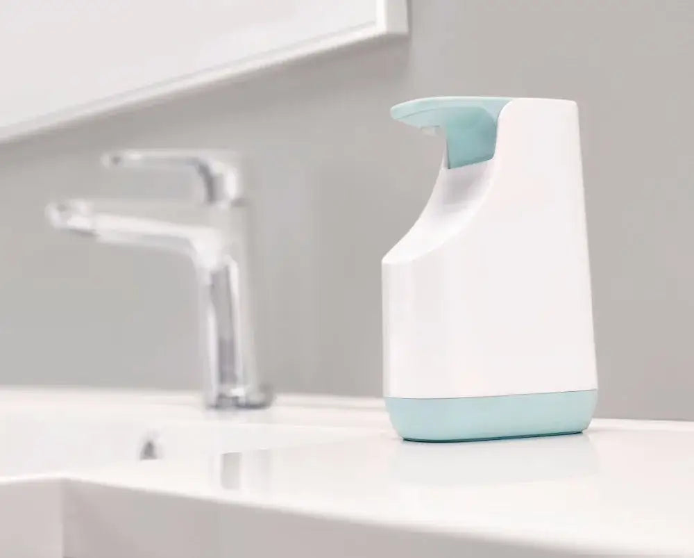 A sleek matte white and teal soap pump dispenser with automatic function on a bathroom countertop