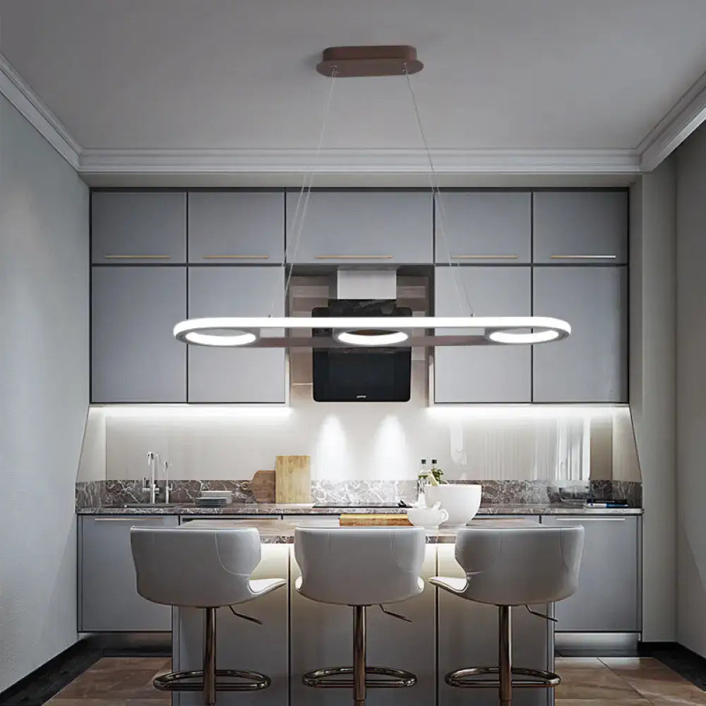 Modern metal white oval pendant light with sleek elongated design and three circular LED bulbs for kitchen island use