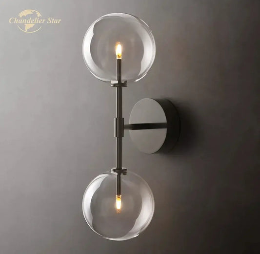 Modern metallic wall sconce featuring two clear glass globe bulbs with a sleek metallic finish for bedroom lighting