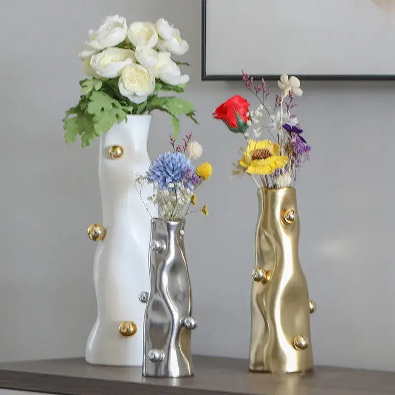 Three modern sculptural decorbites geometric sphere vases in white silver and gold with wavy textures and gold-tone accents