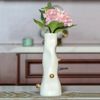 A sleek white ceramic decorbites geometric sphere vase with gold accents holding pink hydrangeas for living room decor