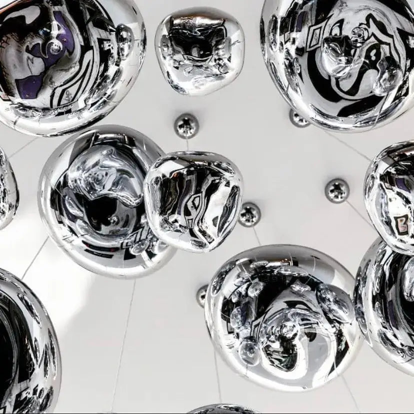 Shiny chrome-finished spherical glass pendant lights with reflective surfaces for modern dining room clusters