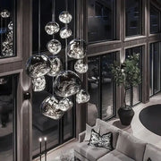Modern metallic glass pendant lights with reflective finish hang in an elegant dining room cluster fixture