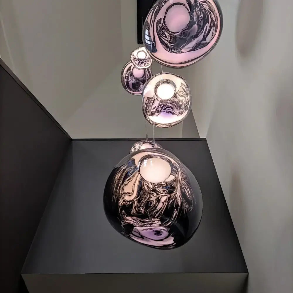 A modern multi-tiered glass pendant light with metallic spherical shades and swirling patterns for dining room use
