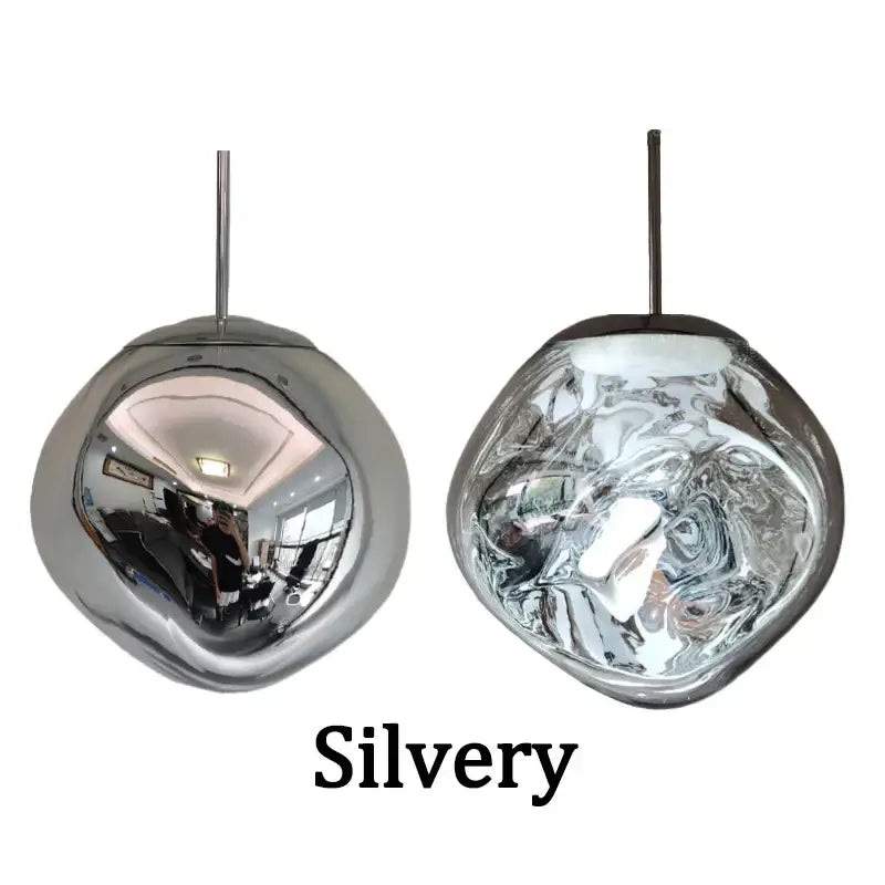 Two modern silver-toned glass pendant lights with reflective organic shades and sleek metal fixtures for dining room
