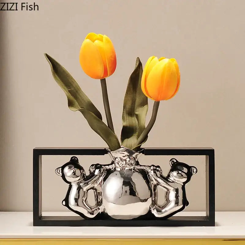 Modern metallic silver ceramic vase shaped like a globe held by bears with vibrant orange artificial flowers decorbites elegant square