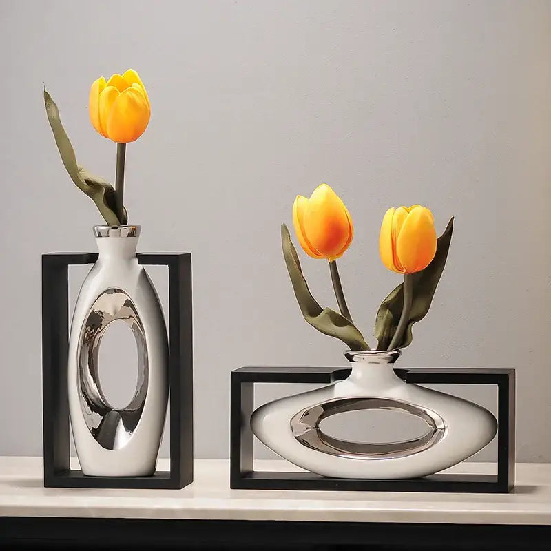 Modern metallic oval ceramic vase in white with silver cutouts holding artificial yellow flowers for decorbites elegant square desk decor