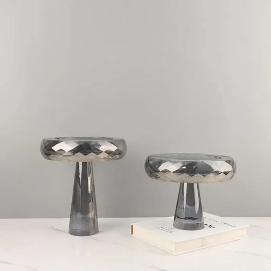Two sleek modern metallic silver geometric glass fruit bowl stands with faceted finish and tapered cylindrical bases