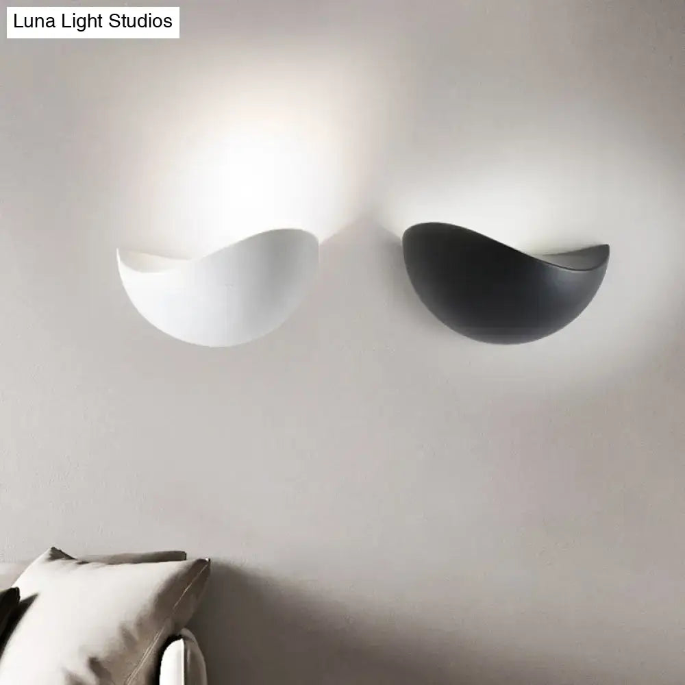 Two minimalist ceramic metallic wall washer light sconces in black and white with smooth curved surfaces for bedroom use
