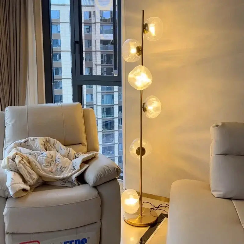 Modern minimalist floor lamp with slender gold-toned metal stand and five warm glass shade led globes for home decor