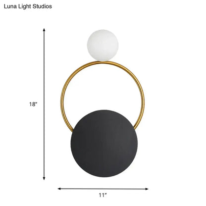 Modern minimalist black and gold wall light with a sleek gold frame, matte black disc, and white spherical lampshade