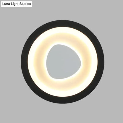 Modern minimalist black wall light with acrylic shade featuring a glowing warm white ring and irregular central opening