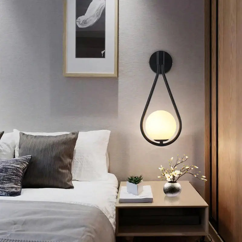 Black teardrop-shaped wall lamp with frosted glass ball led bulb designed for modern minimalist bedroom lighting