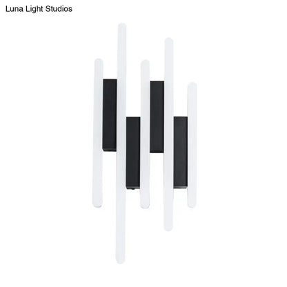 Modern minimalist black and white led wall sconce with sleek vertical bars emitting warm white light for bedroom use