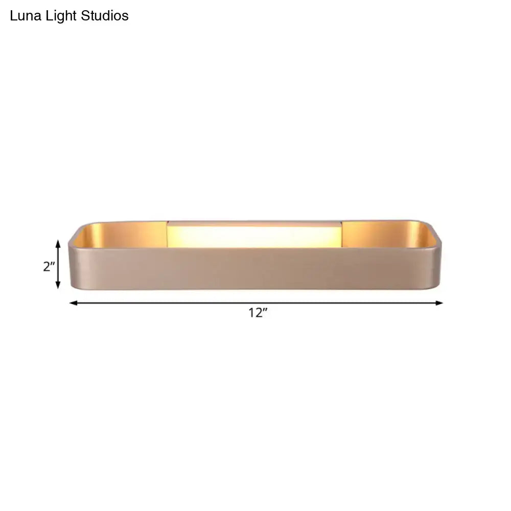 A sleek rectangular wall lamp with brushed gold finish and illuminated center panel for modern minimalist bedrooms