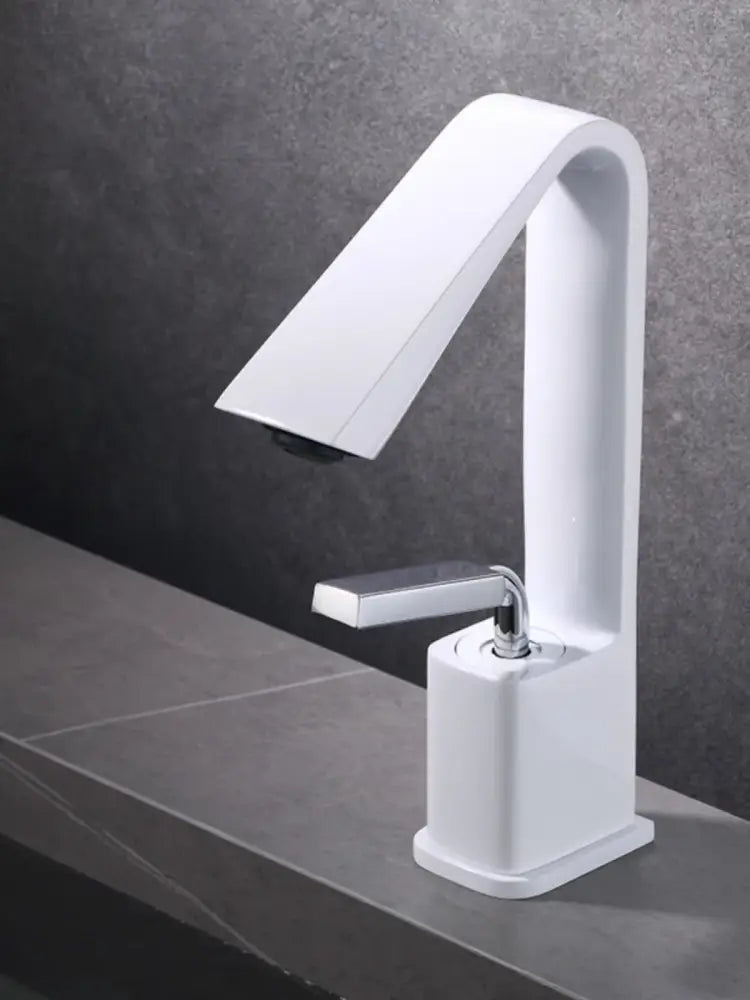 Modern minimalist brush gold basin faucet with a sleek white ceramic spout and chrome finish handle for bathroom sink