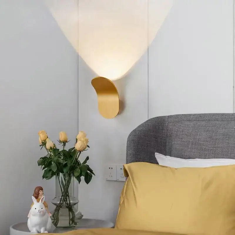 Gold-toned modern minimalist curved metal led wall lamp with sleek base and soft diffused light for living room wall lamps