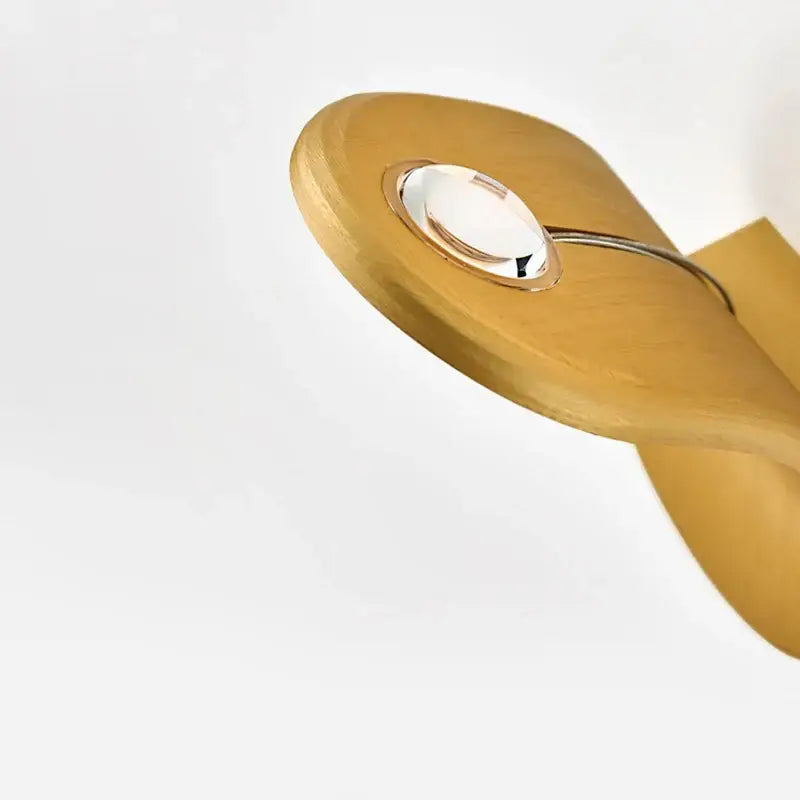 A sleek light wood spoon with a polished metal ring and glass accent featured alongside modern minimalist curved led wall lamps