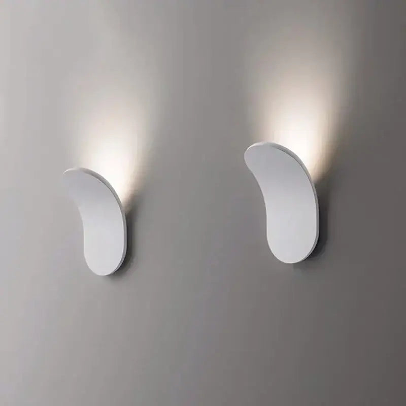 Modern minimalist curved metal led wall lamps with sleek white design emitting warm light for living room use