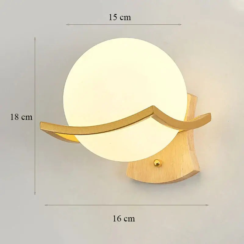 Modern wall lamp with a round frosted glass shade and glass shade gold accents on a light wood base for bedroom
