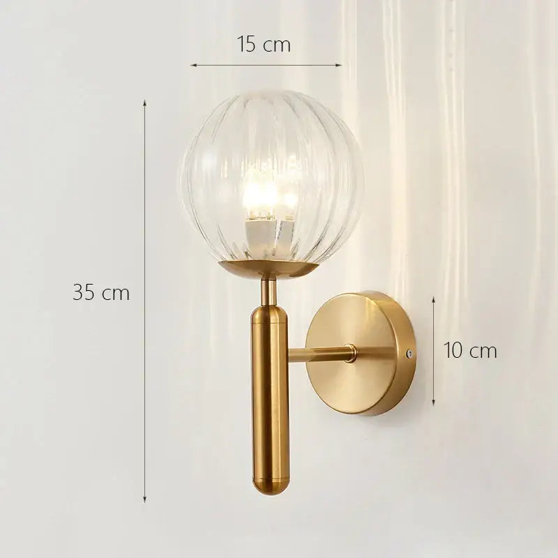 A sleek brass wall lamp with a clear ribbed glass shade gold glass shade for modern minimalist bedroom lighting