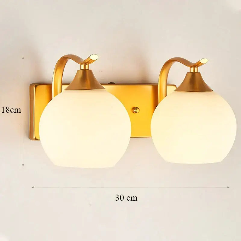 Modern minimalist wall lamp with gold curved arms and two spherical frosted glass shades for bedroom use