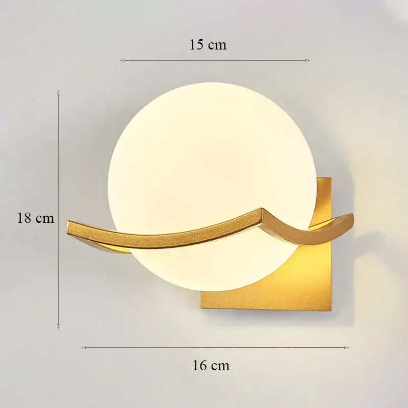 Modern minimalist wall lamp with gold-toned metal and a frosted circular glass shade for bedroom lighting