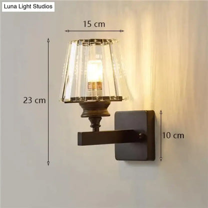 A modern minimalist wall lamp with a dark bronze base and fluted crystal glass shade for elegant bedroom lighting