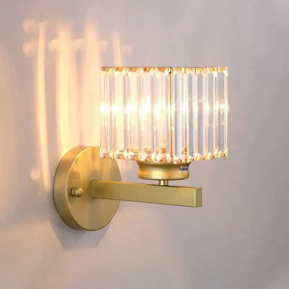 Modern minimalist gold wall lamp with rectangular crystal shade made of vertical faceted glass rods for bedroom use