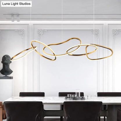 Modern minimalist golden led hanging light fixture with interconnected circular rings above a dining table