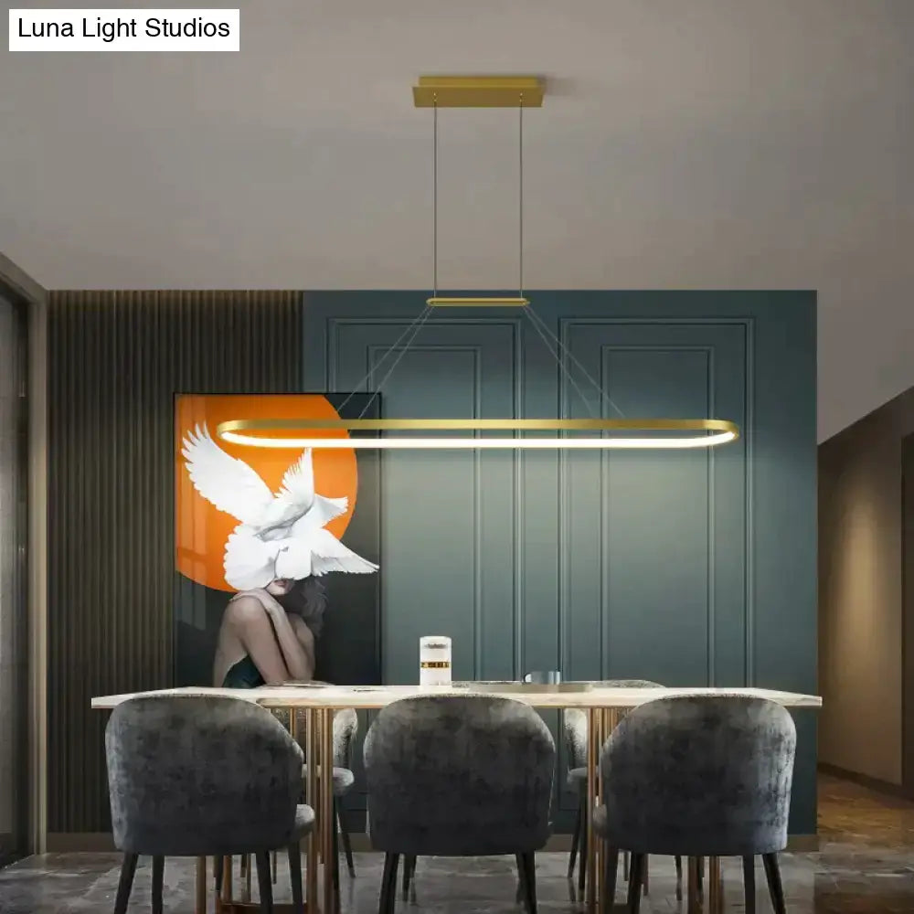 Gold-toned rectangular salix v pendant light with modern minimalist led design hanging above dining table