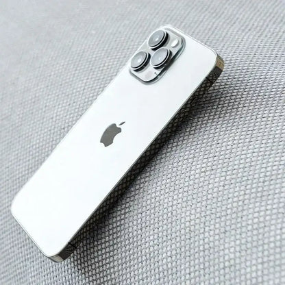 Silver iphone 13 pro with sleek reflective glass back and triple-camera system next to modern minimalist light green panda sofa mat