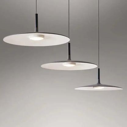 Three modern minimalist led ufo pendant lights with black stems and white shades emitting soft glow for dining room