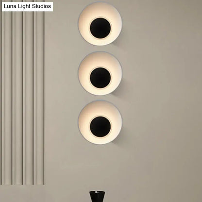 Three modern minimalist wall lamps with circular matte white finish and black central openings for living room use
