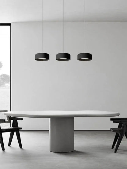 Three sleek black cylindrical pendant lights in a modern minimalist dining space by decorbites designer led chandelier