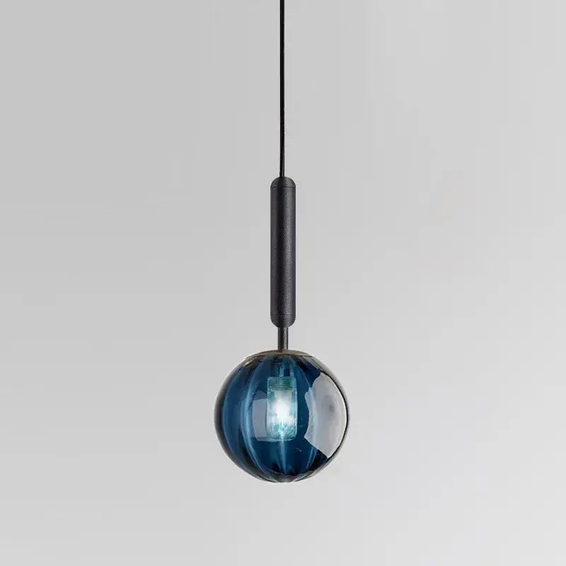 Modern glass pendant light in blue with a matte black painted iron stem for dining room illumination