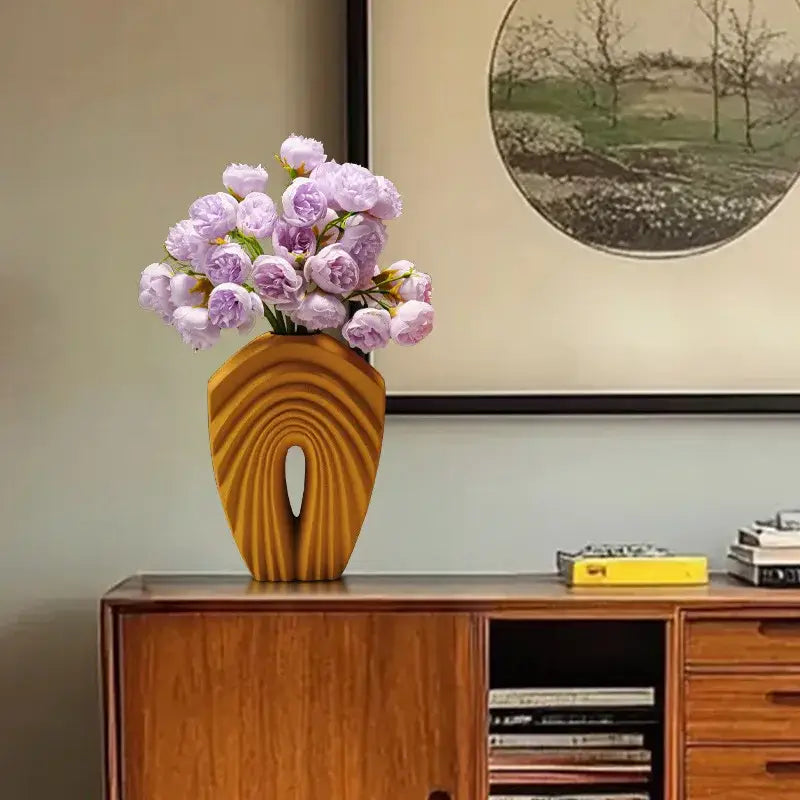 A sleek golden-brown wooden vase with concentric grooves and lavender peonies complements geometric folds ceramic decorbites