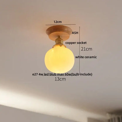 A warm glowing white ceramic globe ceiling lamp with brass copper socket and ash wood mount for modern nordic decorbites clear glass led