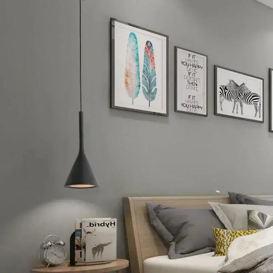 Black metal modern nordic pendant light with conical design hanging above wooden nightstand in bedroom setting