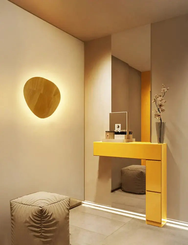 A sleek mustard-yellow console table with minimalist design and integrated drawers complements a wooden wall lamp