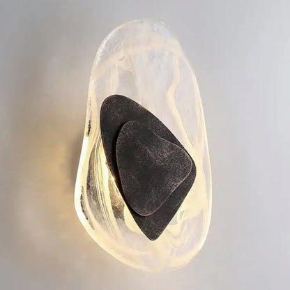 Transparent smooth glass container holding three nested black guitar picks for modern nordic sconce light fixture